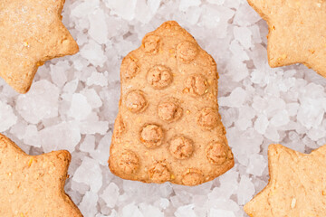 Top view of bell and star shaped Christmas cookies on background of decorative ice pieces.