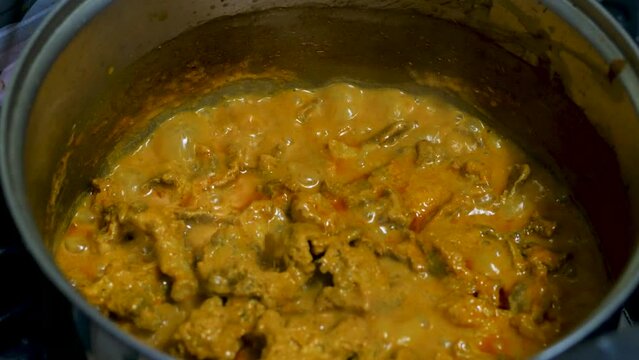 Red curry boiling on a pot with eggpalnt and herb. Making of red curry with chicken, Thai food, Pa neang.