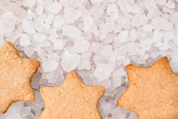 Top view of star shaped Christmas gingerbread cookies on blurred background of ice pieces. Festive Christmas and New Year background with copy space for greeting text.