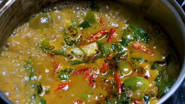 Red curry boiling on a pot with eggpalnt and herb. Making of red curry with chicken, Thai food, Pa neang.