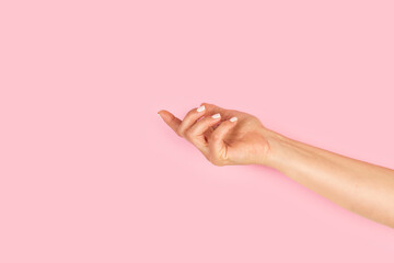 Mano de mujer elegante con la palma vacía hacia arriba sobre un fondo rosa pastel liso y aislado. Vista de frente y de cerca. Copy space - obrazy, fototapety, plakaty