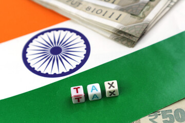 The word Tax on the background of the Indian flag and rupees. Taxation in India. Selective focus....