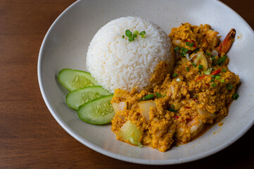 Stir Fried Prawns with Curry Powder on a wooden table, Stir Fried Shrimp with curry powder with fried egg rice, Thai food thai cuisine food on dish, Copy space.