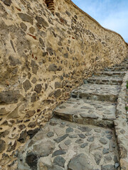 Stairs leading up in ancient fortress against blue sky with clouds. Copy space. Selective focus.