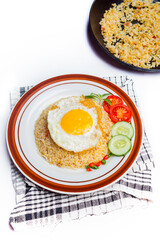 Fried rice served with fried egg, sliced ​​tomato, green chili and cucumber in plate isolated on white background. top view.