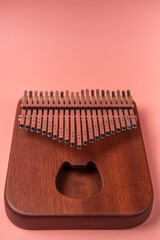 Kalimba or mbira is an African musical instrument. Kalimba is made of wood with metal to create sound. isolated on a pink background