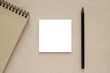 Work desk with square sticky notes, memo pad or notepad mockup, flat lay composition with black pencil and spiral notebook. © IndrePau