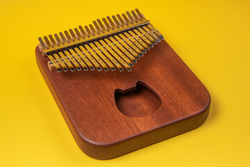 Kalimba or mbira is an African musical instrument. Kalimba is made of wood with metal to create sound. isolated on a yellow background