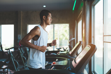 Asian athlete sportsman runner tan skin running on treadmill in fitness club. Cardio workout....