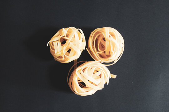 Traditional Italian Pasta Rolled And Baked On Black Background.  Portion Of Raw Fettuccine Or Tagliatelle Or Pappardelle.