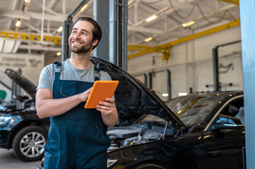Joyful automotive technician standing at the service station