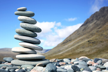 Fototapeta na wymiar pyramid of smooth stones on the background of a mountain. natural balance of life.