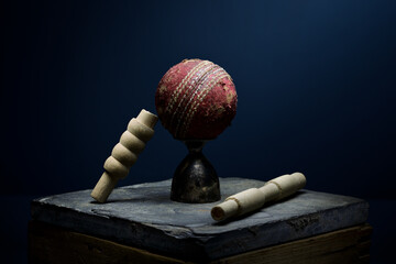 Cricket ball and bails still life in moody light with a blue background - 535822553