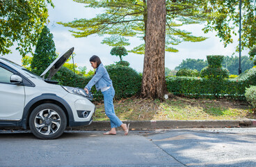 Angry Asian woman and using mobile phone calling for assistance after a car breakdown on street. Concept of vehicle engine problem or accident and emergency help from Professional mechanic