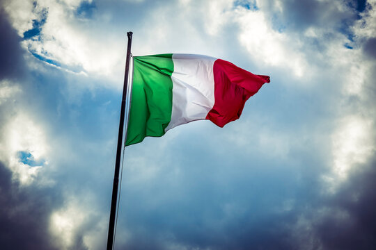 Italian national flag flying against moody sky