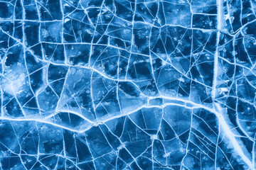 Ice on a frozen river. Background texture of blue ice with cracks in the snow. drone view.