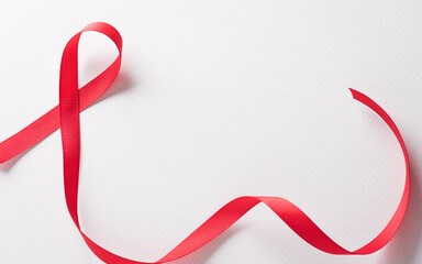 Closeup red ribbon HIV, world AIDS day awareness ribbon on white background. Healthcare and medicine concept.