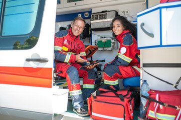 Cheerful paramedics posing for the camera in the ambulance car