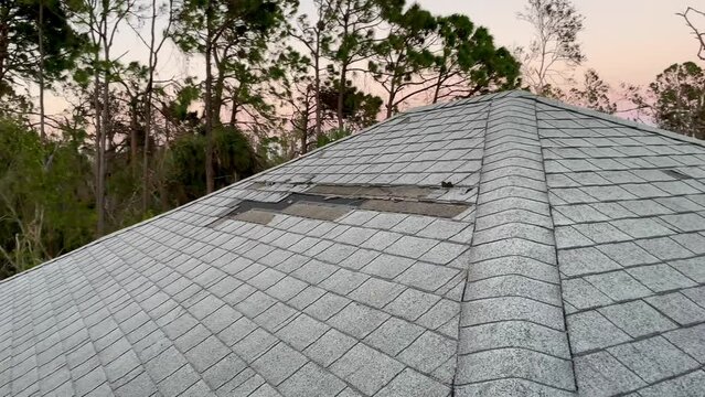 House roof wind damage from hurricane storm torn off shingles 