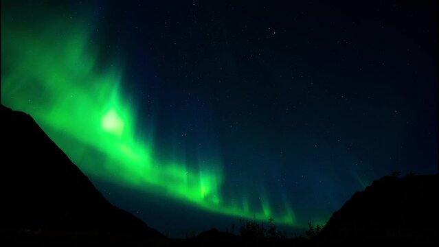Aurora Explosion at Rystad Lofoten Norway with intense green Northern Lights in front of the mountain scenery