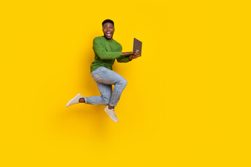 Fototapeta na wymiar Full length body size view of attractive guy jumping using laptop web isolated over vivid yellow color background