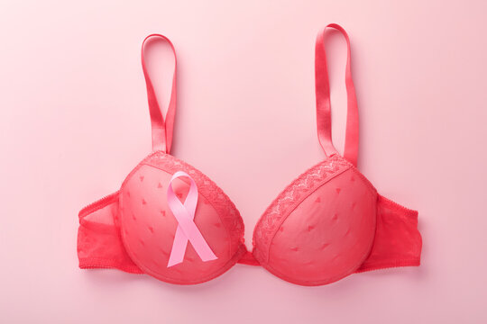 Breast Cancer Awareness Ribbon. Red bra and pink ribbon tape lying on female bra on backgrounds. Breast cancer awareness and October Pink day, world cancer day. Top view. Mock up.