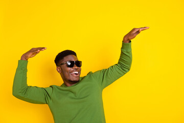 Portrait of attractive cheerful guy dancing moving having fun night club isolated over bright yellow color background