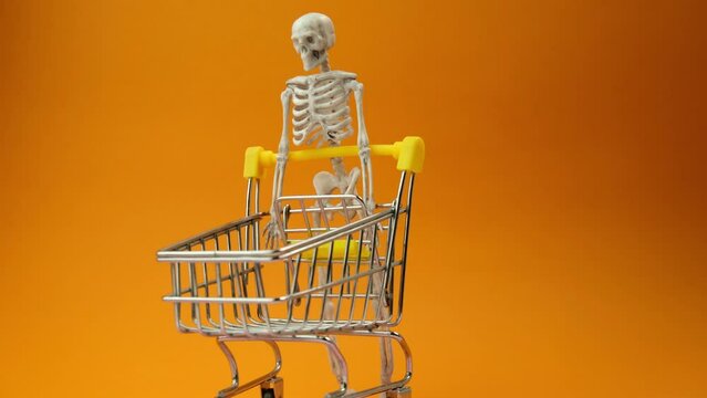 a skeleton is driving a cart from a supermarket on an orange background