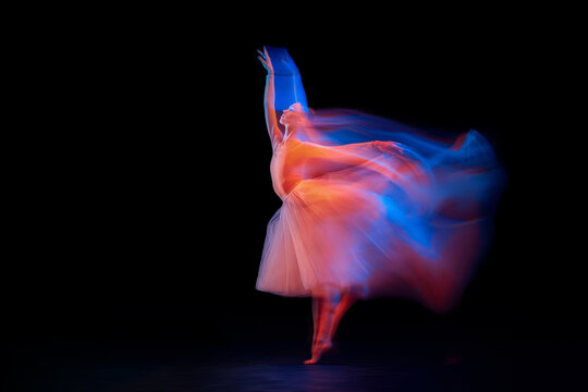 Dance of light and glow. Beautiful grace girl, female ballet dancer dancing isolated over black background in mixed neon light.