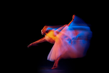 Futurism, fantasy, miracle. Graceful and fragile ballerina in ballet dress in motion isolated over black background in mixed neon light.