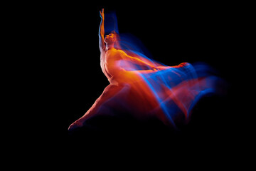 Young graceful and flexible shirtless male ballet dancer dancing isolated on dark background in...