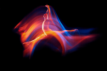 Like a phoenix. Solo performance of flexible adorable male ballet dancer isolated on dark background in glowing colorful neon light. Grace, art, beauty