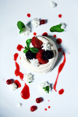 Meringue cake Pavlova with fresh strawberry and blackberry on a white plate. Top view.