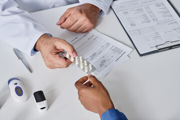 Close-up of doctor giving medicine to patient while they sitting at table