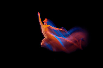 Young graceful and flexible shirtless male ballet dancer dancing isolated on dark background in...