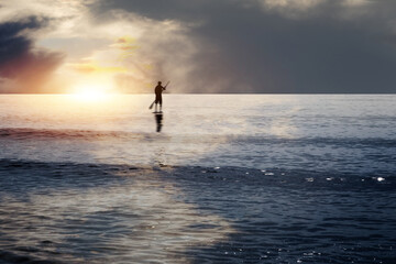 Ein junger Mann auf einem Surfbrett genießt den Sonnenuntergang am Meer