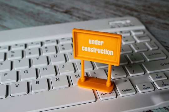 Under construction sign on top of computer keyboard. Computer system under construction, maintenance, repair concept.