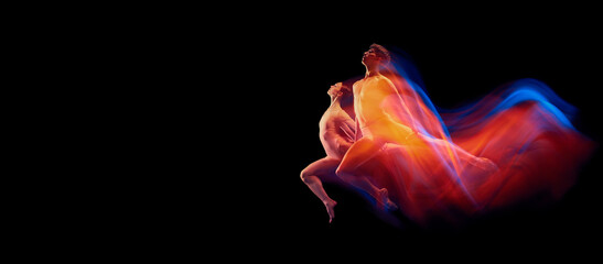 Beautiful couple of graceful and fragile ballet dancers in action isolated over black background in...