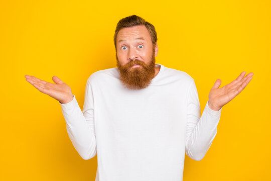 Photo portrait of attractive young man shrugging shoulders puzzled unsure wear stylish white clothes isolated on yellow color background