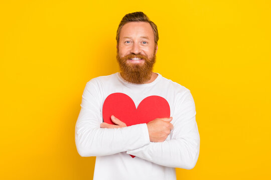 Photo of funny beard ginger man hug heart wear white shirt isolated on yellow color background