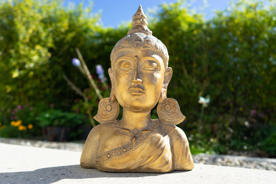 Buddha statue near house in front of garden.
