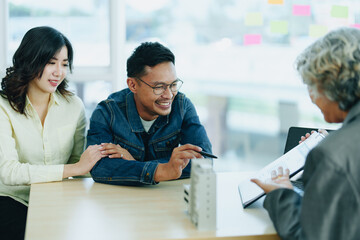 Guarantee Insurance Sign a contract, couple a smiling couple is signing a contract to invest in real estate with the Mortgage officer with the bank