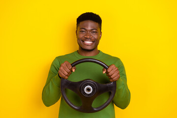 Portrait of attractive cheerful guy holding steering wheel ride way isolated over vibrant yellow color background