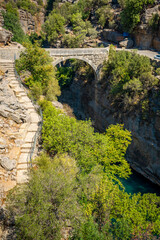 Fototapeta na wymiar Ancient arch bridge over the Koprucay river gorge in Koprulu national Park in Turkey. Panoramic scenic view of the canyon and blue stormy mountain river