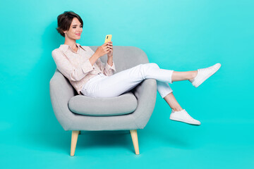 Profile side photo of charming lady stylish outfit sit chair write telegram facebook post empty space isolated on cyan color background