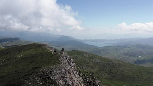 Aerial view of two people celebrating the arrival at the top of a mountain in Mavrovo National Park, North Macedonia