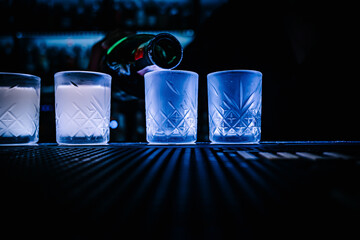 bartender pouring distilled alcohol into a shot glass in bar