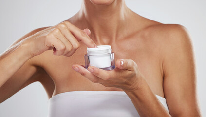 Cream, beauty skincare and hands of woman with product for body wellness against a grey studio...