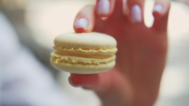 Close up footage female hand holding yellow macaroon and crushing it.