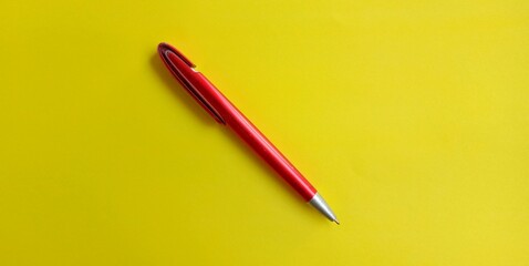 red ballpoint pen or red pen in the photo from above on a yellow background